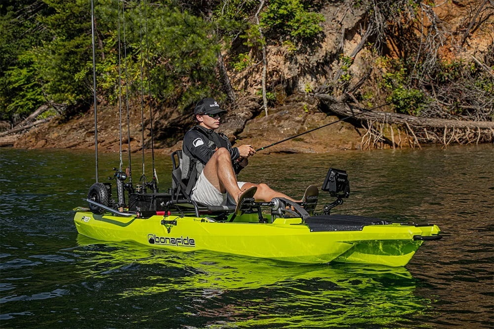 Angler using a pedal-drive fishing kayak on calm water Angler using a pedal-drive fishing kayak on calm water